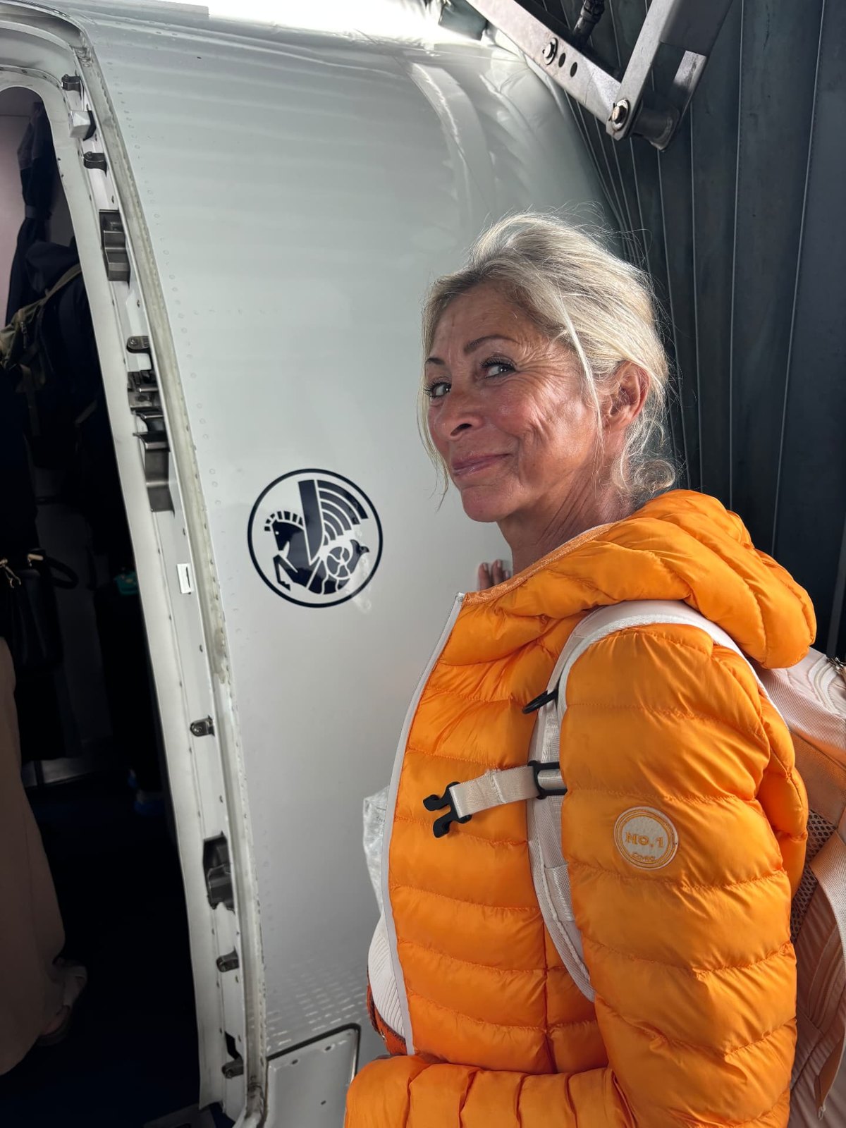 Nathalie souriante à la porte d’un avion, au moment d’embarquer